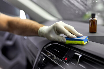 Auto repair man in protective gloves cleaning auto from inside using detergent oils liquid from...