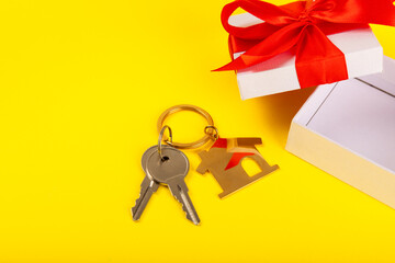 House keys with a keychain in the shape of a house on a textured background.Design element.Real estate and insurance concept.Buying or renting real estate.Apartment as a gift.Copy space.Place for text