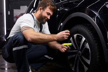 Fototapeta na wymiar Professional Auto Mechanic Repair Man Using Liquid Oil For Lubricating Car Wheels In Auto Service,Side View