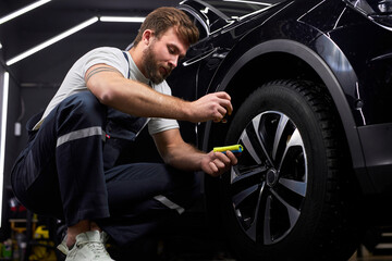 Fototapeta na wymiar Auto Mechanic Repairing Car Wheels, Using Liquid Oil For For Renovation, Apply It On Wheels. Copy Space. Auto Repairing Concept