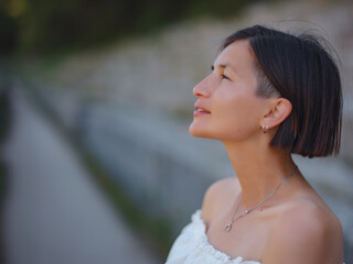 Beautiful Asian young woman in white dress outdoor. Acropolis of Rhodes Famous ruins of ancient settlement with various buildings such as stadium and theater.