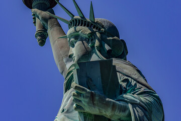 The Statue of Liberty with her crown holding her torch under a stunning blue sky of New York (USA)...