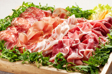 Tray of delicious mixed Italian prosciutto hams and salami with lettuce