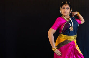 Bharatanatyam mudra performed by woman Indian classical dancer on black background with writing space