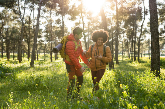 couple in love on an excursion through the forest with backlight walking among flowers