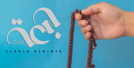 Jummah Mubarak blessed happy Friday Arabic calligraphy, Selective focus image hand of Muslim woman holding prayer beads. - obrazy, fototapety, plakaty