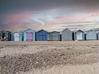 Obraz na płótnie Canvas The beautiful beach huts of Mersea Island set against a dramatic sky
