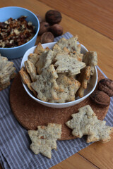 Walnut cookies in shape of a tree ina white bowl with dry walnuts on woooden table 