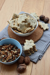 Walnut cookies in shape of a tree ina white bowl with dry walnuts on woooden table 