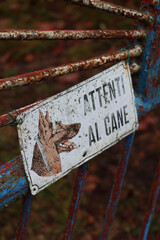 Close-up of “Attenti al cane” (italian language) Beware of Dog Sign on blue and rusty old gates © saratm