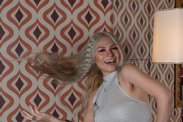 Silver blonde girl. With hair thrown in the air, sleeveless gray sweater. Laughing.