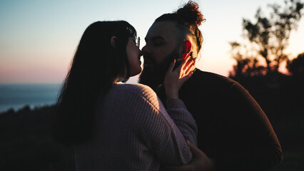 Young engaged couple kissing at sunset