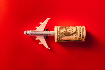 Toy airplane, twisted dollar bill, red surface.Copy space.