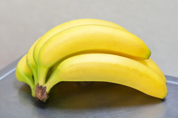 A branch of yellow ripe bananas on scales in a store.