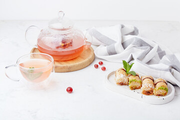 Aesthetic autumn glass teapot of natural healthy cranberry tea and traditional turkish baklava. Lagom home.