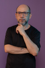 Bearded, bald white man wearing prescription glasses wearing black clothing looking at the camera posing for a photo.