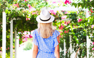 Blond girl in straw hat in front of pink bougainvillea flowers