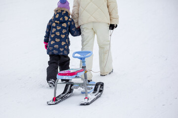 Kids with sledge climbing at the snowy hill on winter park in Bakuriani