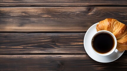 A cup of hot americano coffee with fresh baked croissants on a wooden table, a warm cozy atmosphere. French breakfast. Top view, copy space background.