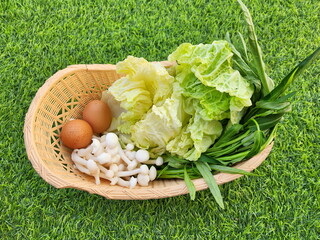 Arrange stir-fry into cream colored plastic basket placed : consisting of Chinese cabbage, golden needle mushroom, vermicelli, Chinese morning glory, eggs. All used for eating with Thai BBQ, sukiyaki.