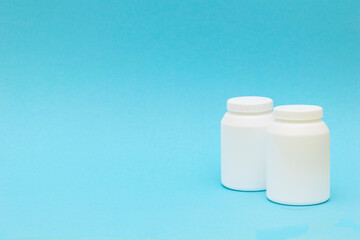 two pill bottle, medicine container for vitamins on blue background.
