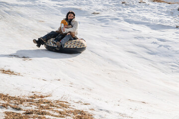Fototapeta na wymiar happy woman mother with child son tubing on a slide in winter with snow
