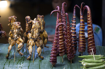 Street food in a Vietnamese market - whole frogs and octopus tentacles are offered for sale