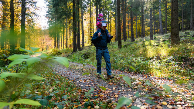 Papa und Kind wandern durch den Wald im Herbst