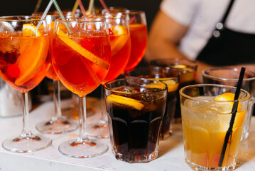 Aperol Spritz Cocktails Close-up with Garnishes. An inviting selection of colorful cocktails, including Aperol Spritz and Cuba Libre, adorned with citrus slices, ready to be enjoyed at a social event.