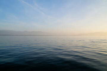 Obraz premium the tranquil transparent waters of lake Constance (Bodensee) with the Swiss Alps in the background at sunset on Lindau island, Germany