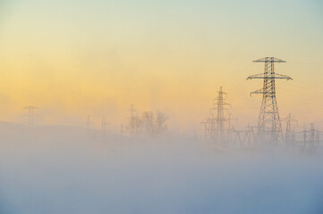 Beautiful and atmospheric scene of a winter morning. High voltage power lines add an element of...