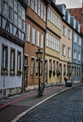 Fototapeta na wymiar Blick in die Strasse einer Altstadt, mit verschiedenfarbigen Häusern und an Strassenlaternen geparkten Fahrrädern