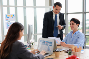 Asian businessperson colleagues discussing with computer in office.