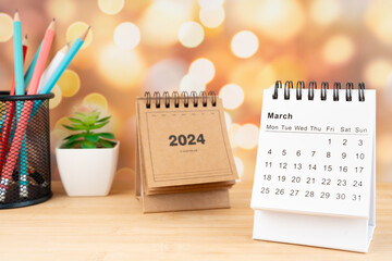 White March 2024 desk calendar on wooden table with gold light bokeh background.
