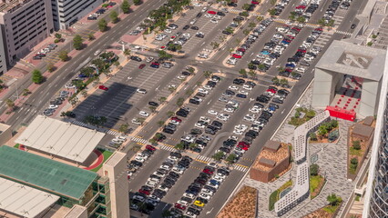 Aerial view of many colorful cars parked on parking lot with lines and markings for parking places all day timelapse. Dubai