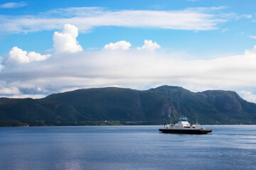 Car ferry crossing the Fjord with mountains in the background