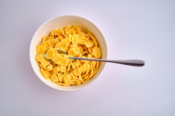 Corn flakes in a red bowl on a white background. Delicious sweet breakfast. Nutrition and health concept
