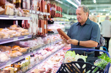 Older man picking out sausage to buy in grocery store