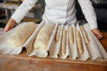 Woman baker or pastry cook making fresh bread in local bakery