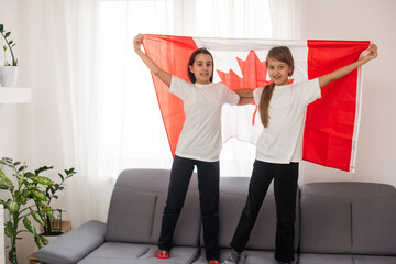 Happy Canada Day Celebration. Two girls with big Canada flag in their hands. Young Canadian...