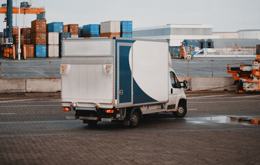 Naklejka premium Cargo Truck In The Port. Modern Commercial Vehicle With Hydraulic Remotely Operated Ramp. Commercial Vehicle For Door-To-Door Goods And Post Delivery. Logistics Transport With Good Capacity