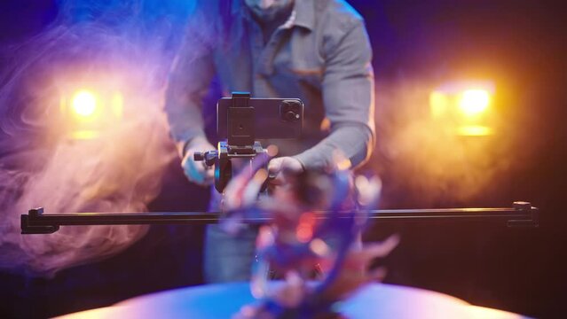 Filmmaker recording product video with smartphone on slider 4K