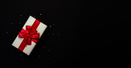 Light yellow gift box with red bow on black background