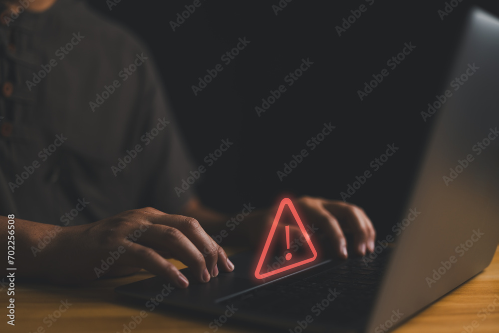 Poster User is using computer with triangle caution warning sign for notification error and maintenance concept. Hacker attacks and hacking data, cyber crime, Ransomware, Phishing, Spyware, cybersecurity..
