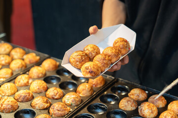 屋台で職人がたこ焼きを焼く写真