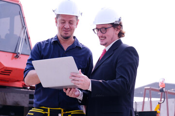 Engineer in safety helmet holding laptop working in industrial factory.