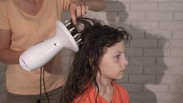 Mom with child using hair dryer. A mother dry daughter hair with blow dryer in the bathroom.