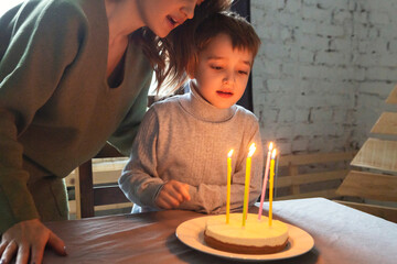 Little preschool caucasian boy blowing out candles on homemade birthday cake at home, kid making...