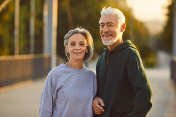 Portrait of active senior happy smiling couple family standing in city park after doing workout in...