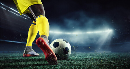 Cropped image of African man's legs, football player in yellow uniform on 3d arena playing, hitting ball. Evening outdoor match. Concept of sport, game, competition, championship. 3D render - obrazy, fototapety, plakaty